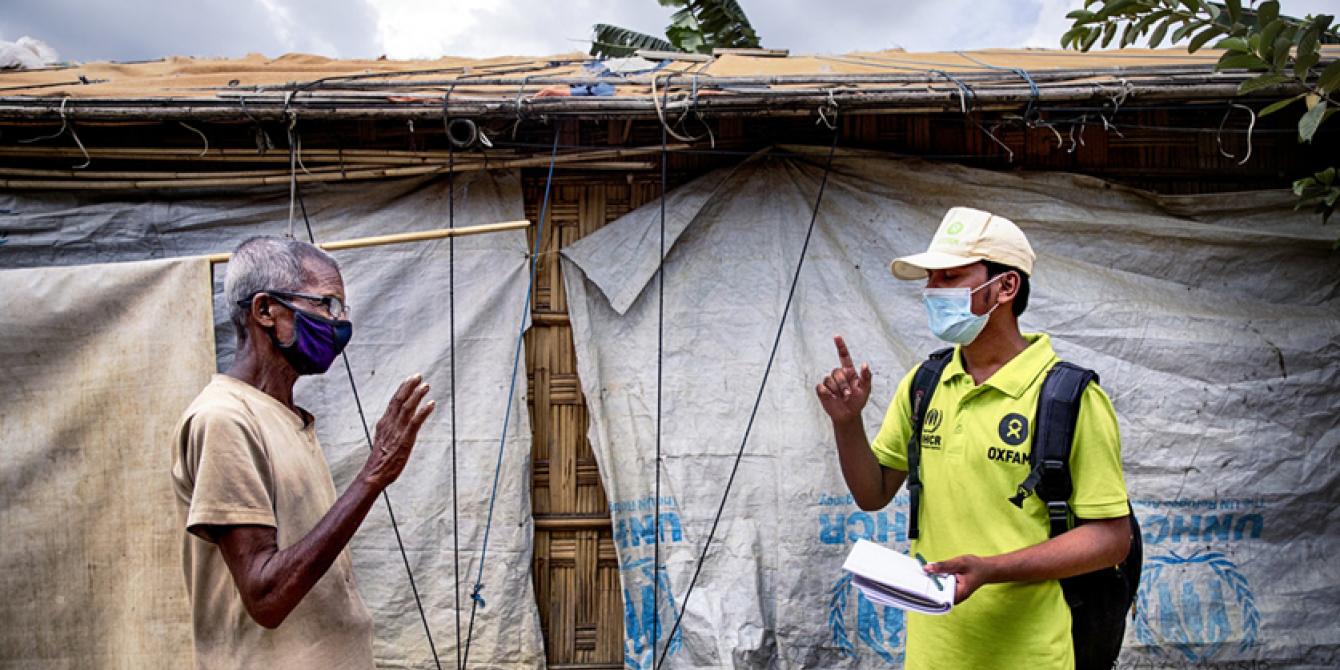 Oxfam volunteer Zahid Hossain, age 20, talking to Abdul Malek, age 80, about the precautions elderly people should take to prevent Covid-19. Cox’s Bazar refugee camp, Bangladesh. Photo: Fabeha Monir